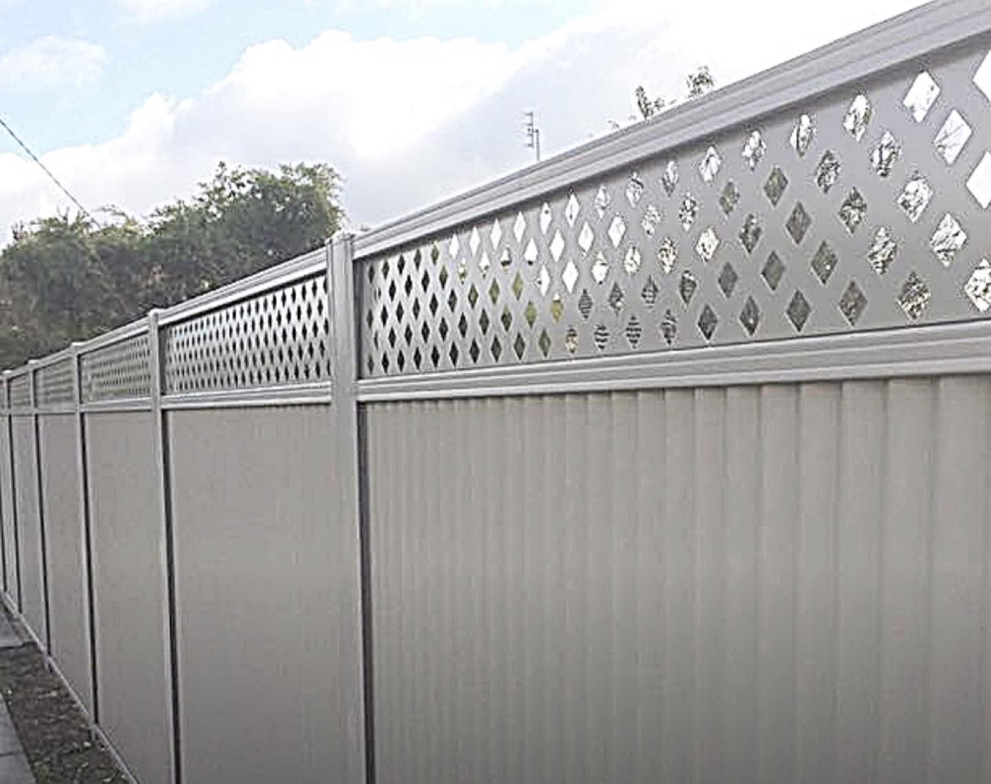 A cream Colorbond fence finished with a diamond lattice topper