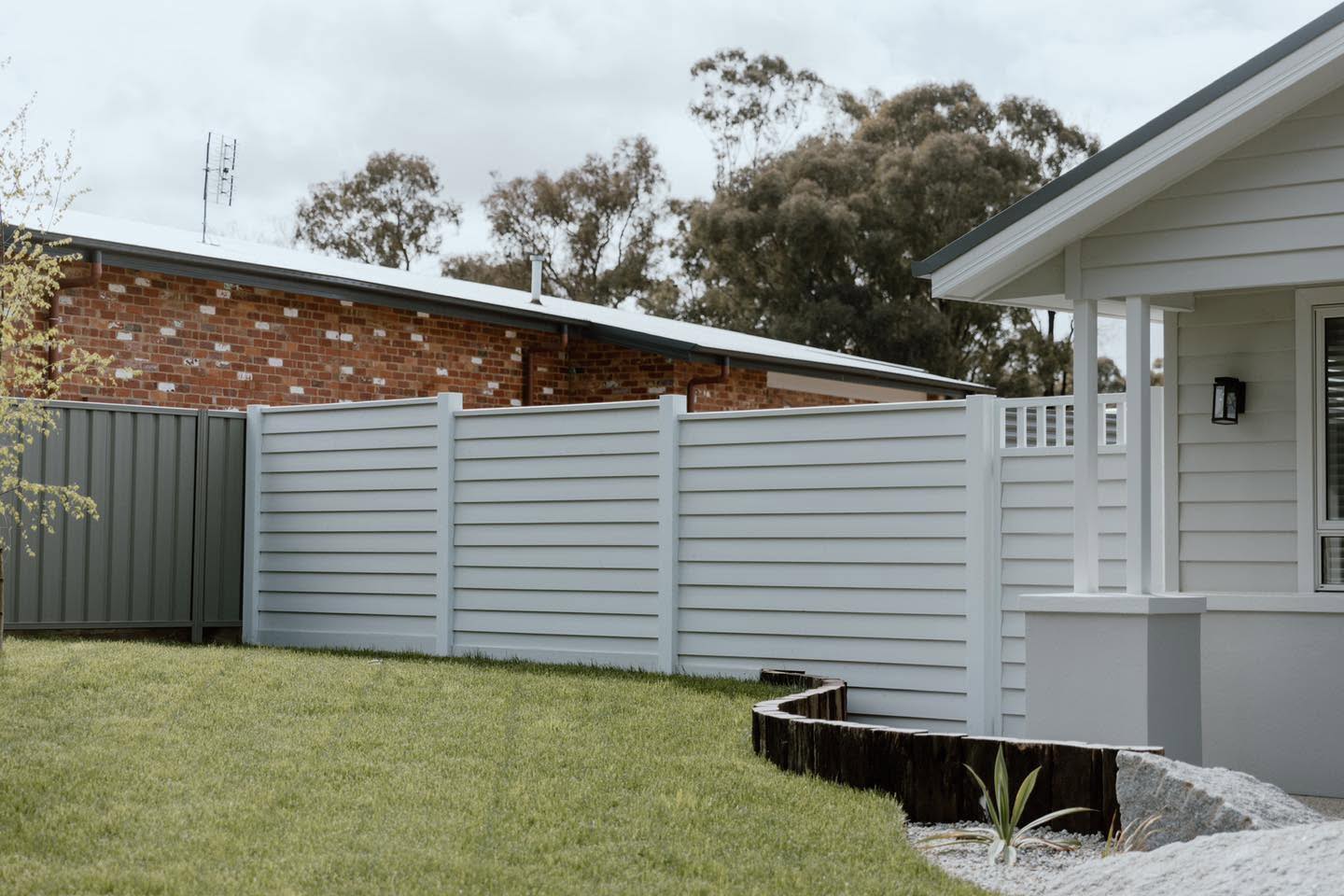 A new hardwood picket fence running beside a driveway