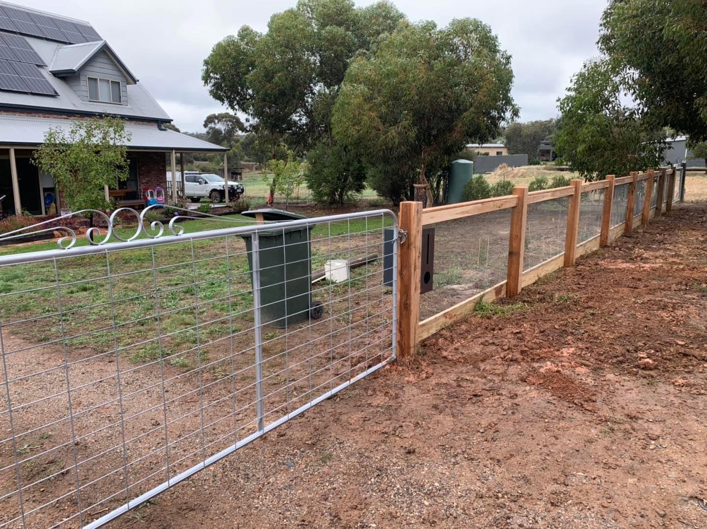 A timber post and rail fence with wire infill along a rural boundary