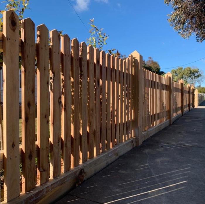 A new hardwood picket fence running along a driveway
