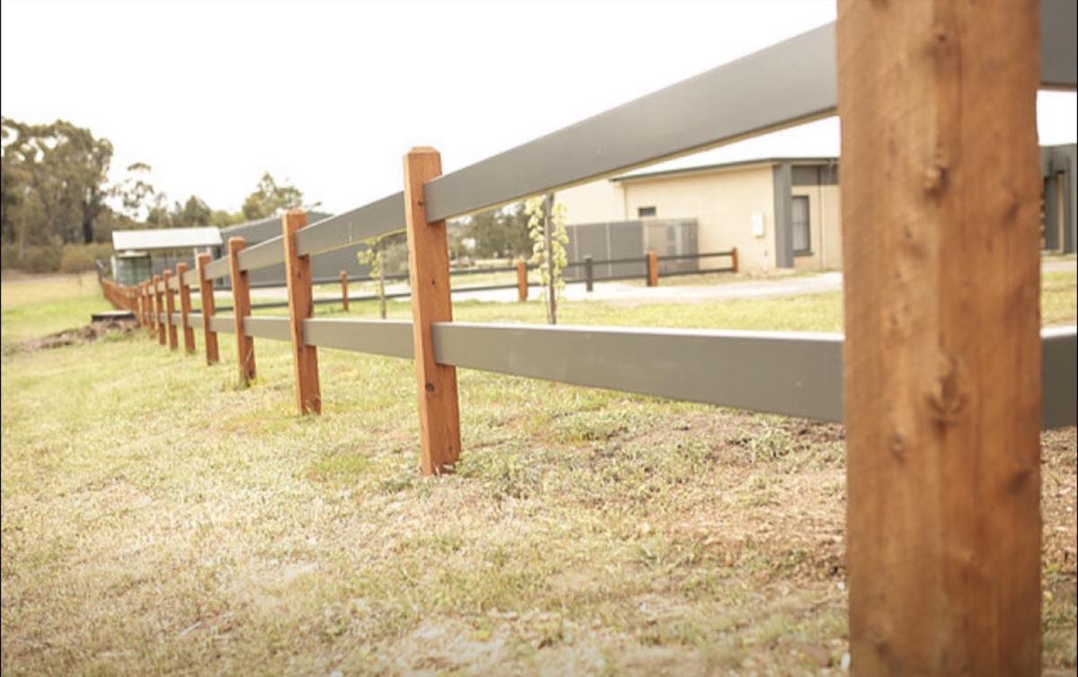 A timber post and rail fence with wire infill along a property boundary