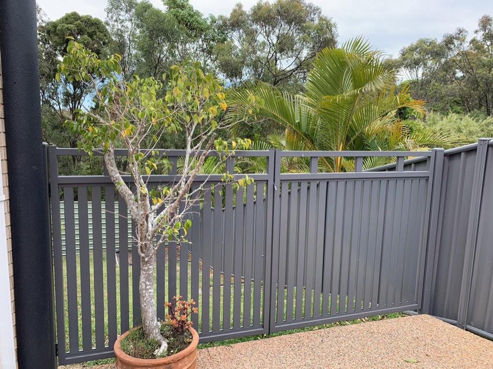 A charcoal Colorbond fence with a slatted top panel beside a garden bed