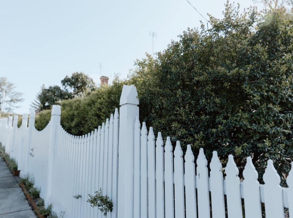 A white timber picket fence curving along a front boundary