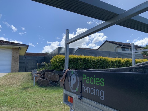 The Pacies Fencing trailer parked in front of a finished charcoal fence with a slatted top