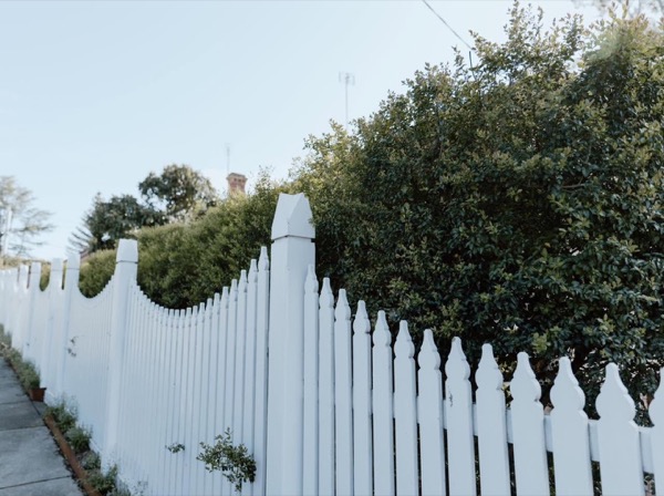 A white timber picket fence curving along a front boundary
