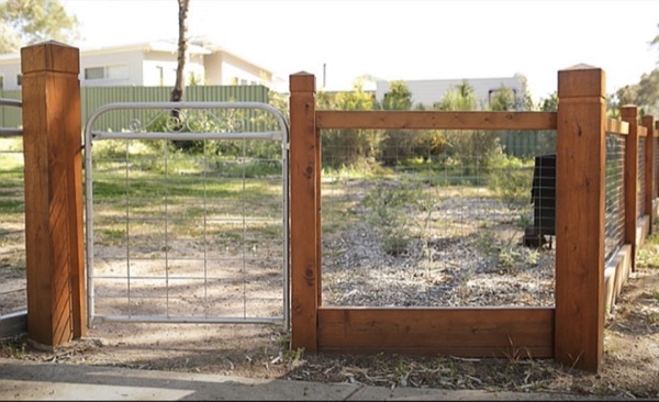 A timber-framed gate with wire infill at the entrance to a block