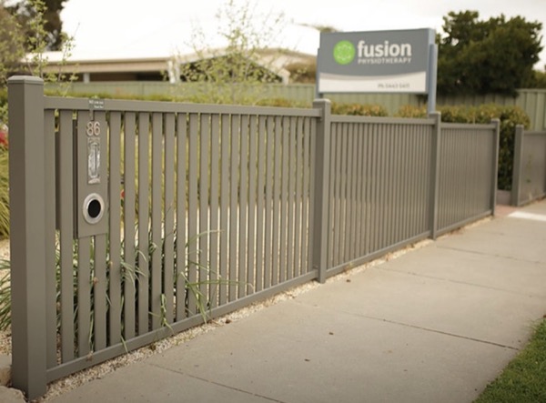 A powder-coated aluminium sliding gate and fence along a commercial footpath