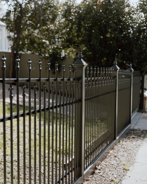 A black powder-coated aluminium fence and matching gate along a footpath