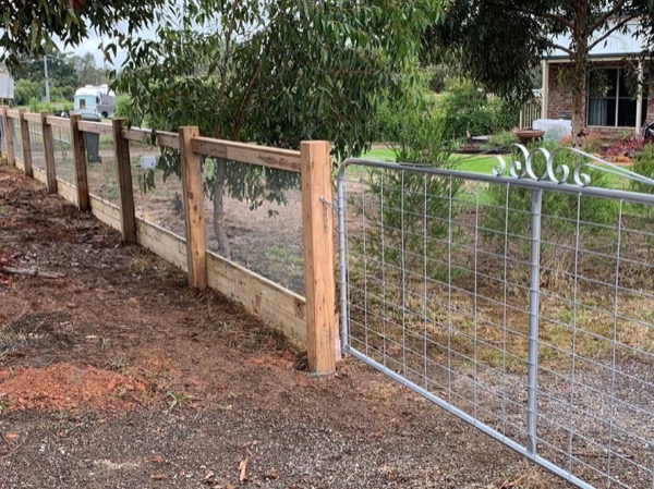 A wire mesh fence on timber posts along the edge of a block
