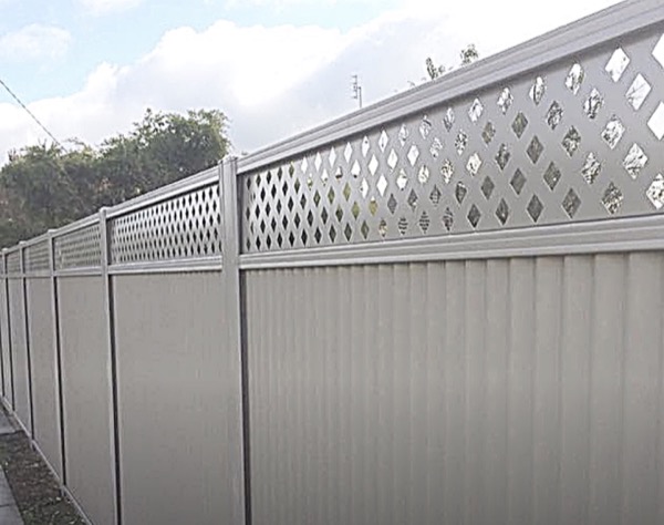 A cream Colorbond fence finished with a diamond lattice topper