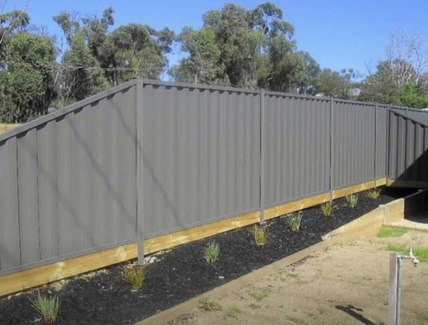 A long run of pale Colorbond fencing seen from one end