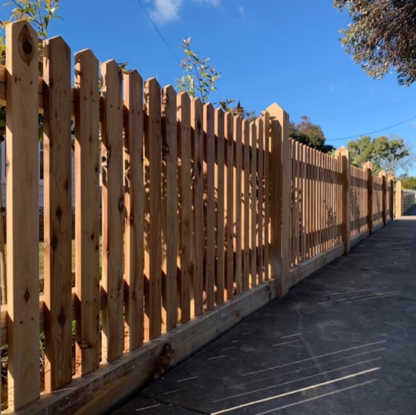 A hardwood picket fence running the length of a sealed driveway